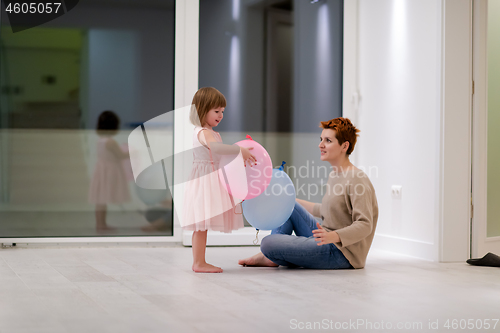 Image of mother and cute little daughter playing with balloons