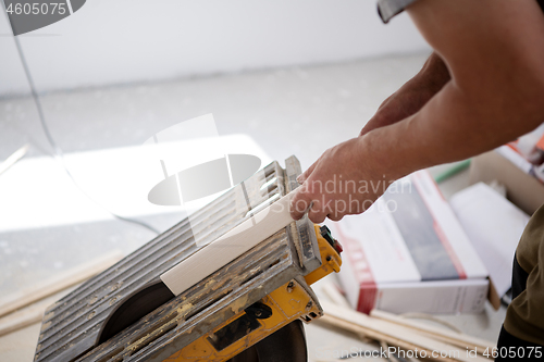 Image of Man cutting laminate floor plank with electrical circular saw