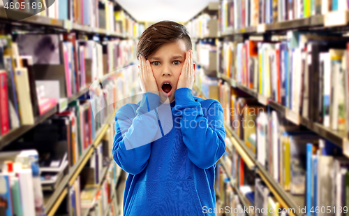 Image of terrified boy over book shelves at library