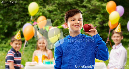 Image of smiling boy with red apple at birthday party