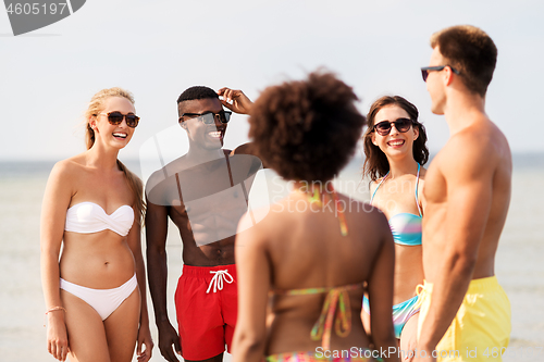 Image of happy friends hugging on summer beach