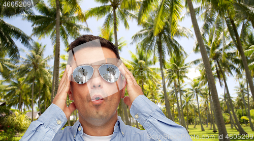 Image of surprised man in sunglasses over tropical beach