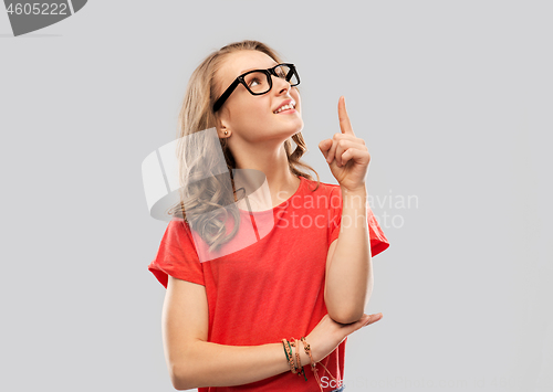 Image of smiling student girl in glasses pointing finger up