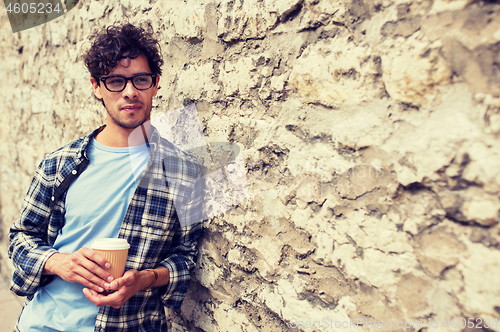 Image of man in eyeglasses drinking coffee over street wall