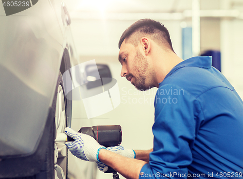 Image of mechanic with screwdriver changing car tire