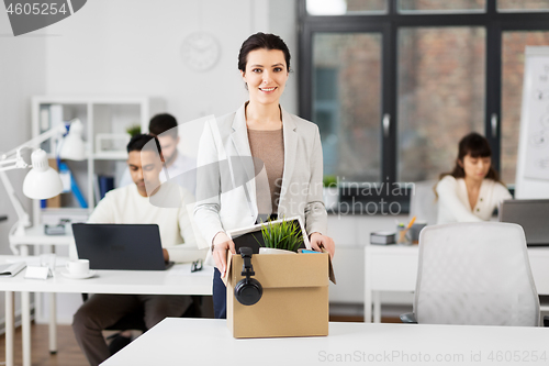 Image of happy businesswoman with personal stuff at office