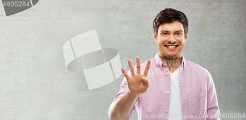 Image of man showing four fingers over grey concrete wall