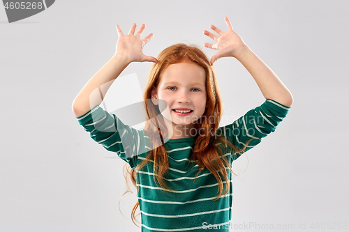 Image of red haired girl having fun and making big ears