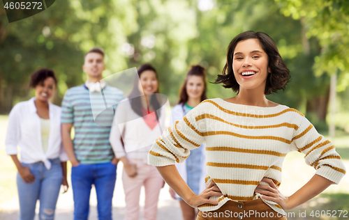 Image of smiling woman with hands on hips over summer park