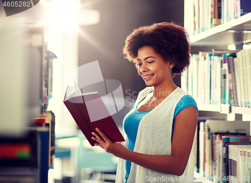 Image of happy african student girl reading book at library