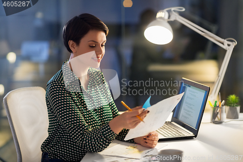 Image of businesswoman with papers working at night office