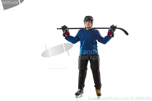 Image of Young female hockey player with the stick on ice court and white background