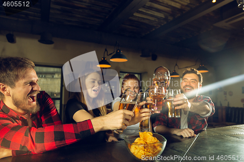 Image of Sport fans cheering at bar, pub and drinking beer while championship, competition is going