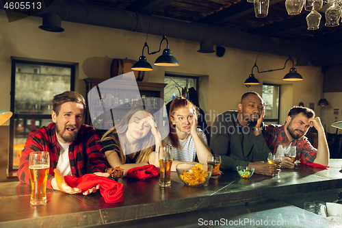 Image of Sport fans cheering at bar, pub and drinking beer while championship, competition is going