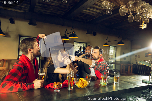 Image of Sport fans cheering at bar, pub and drinking beer while championship, competition is going