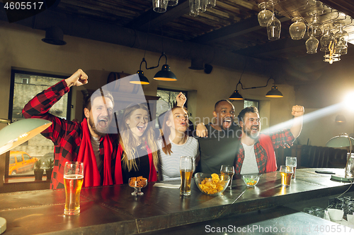 Image of Sport fans cheering at bar, pub and drinking beer while championship, competition is going