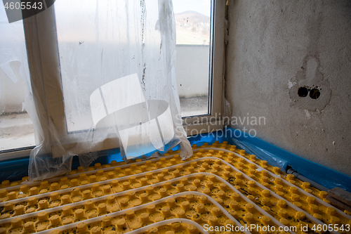 Image of yellow underfloor heating installation with white pipes