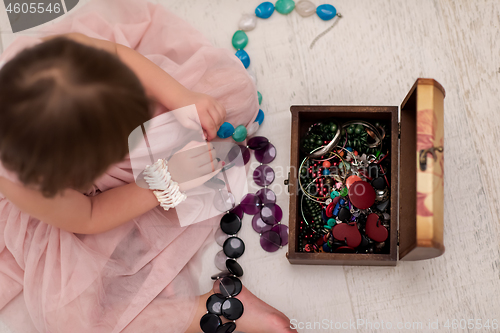 Image of little girl enjoying while playing with mother\'s jewelry