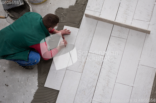 Image of worker installing the ceramic wood effect tiles on the floor