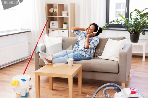 Image of woman in headphones resting after home cleaning