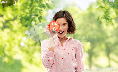 Image of happy young woman in pajama with alarm clock