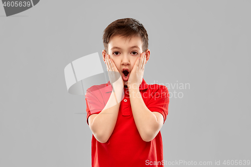 Image of shocked little boy in red t-shirt touching face