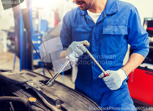 Image of mechanic man with wrench repairing car at workshop