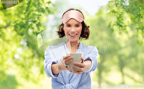 Image of woman in pajama and sleeping mask drinking coffee