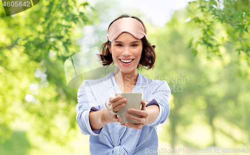 Image of woman in pajama and sleeping mask drinking coffee