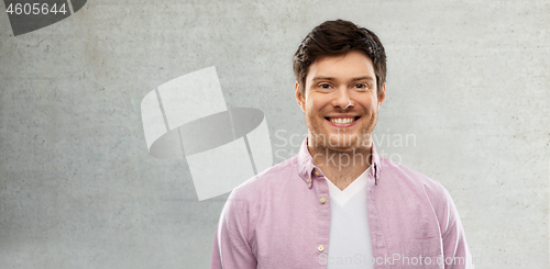 Image of smiling young man over grey concrete wall