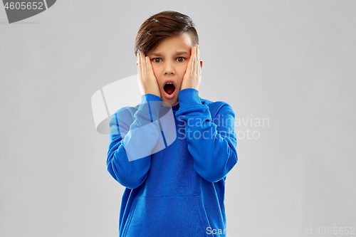 Image of shocked or scared boy touching face