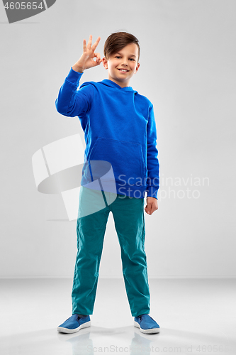Image of boy in blue hoodie showing ok hand sign