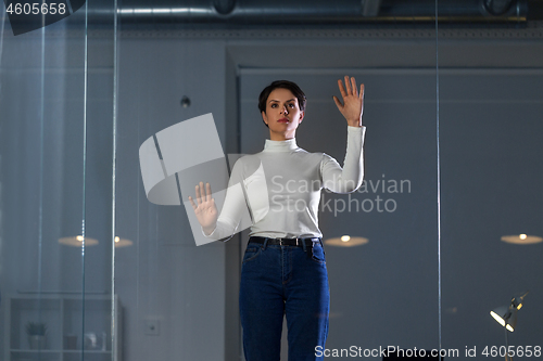 Image of businesswoman using glass wall at night office