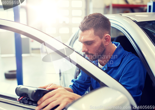 Image of mechanic man with diagnostic scanner at car shop