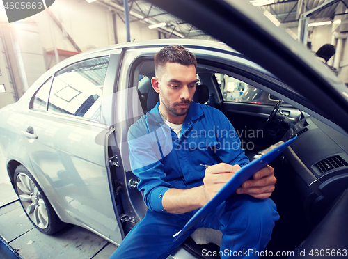 Image of auto mechanic man with clipboard at car workshop