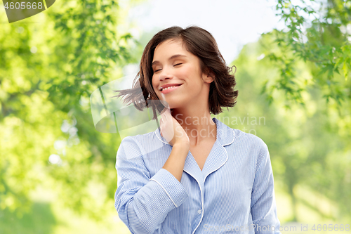 Image of happy young woman in pajama over grey background