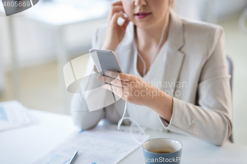 Image of businesswoman with earphones and smartphone