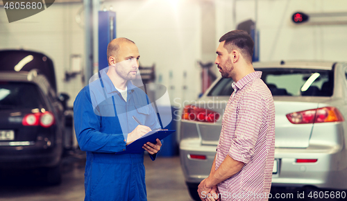 Image of auto mechanic with clipboard and man at car shop