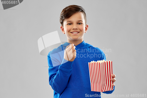 Image of happy smiling boy in blue hoodie eating popcorn