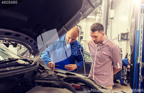 Image of auto mechanic with clipboard and man at car shop