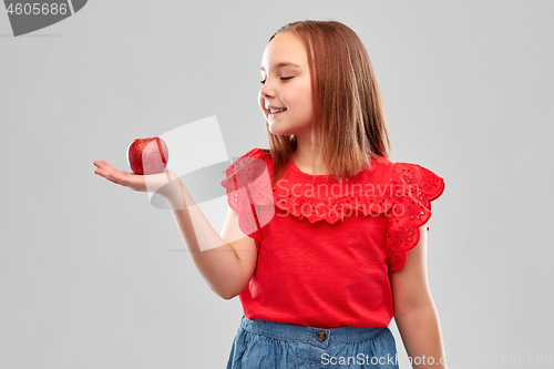 Image of beautiful smiling girl holding red apple on palm