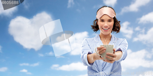 Image of woman in pajama and sleeping mask drinking coffee