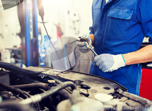 Image of mechanic man with wrench repairing car at workshop