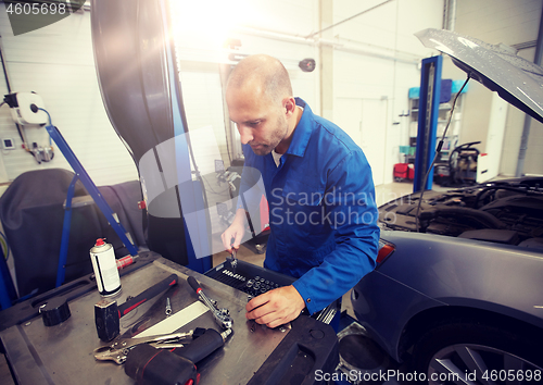 Image of mechanic man with wrench repairing car at workshop