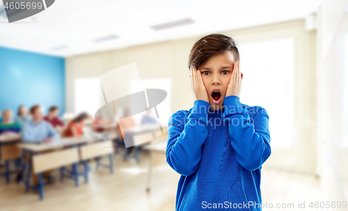 Image of shocked or terrified boy touching face at school