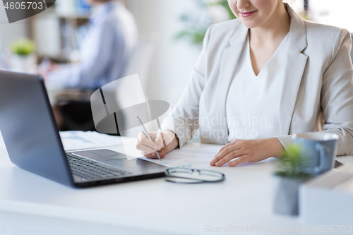 Image of businesswoman with papers working at office