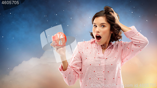 Image of shocked young woman in pajama with alarm clock