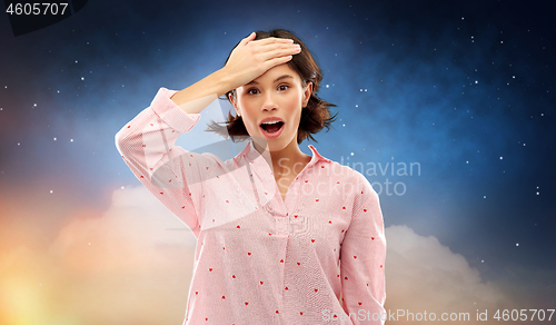 Image of confused young woman in pajama over night sky