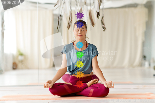 Image of woman meditating in lotus pose at yoga studio