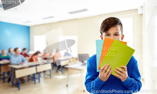 Image of shy student boy hiding behind books at school